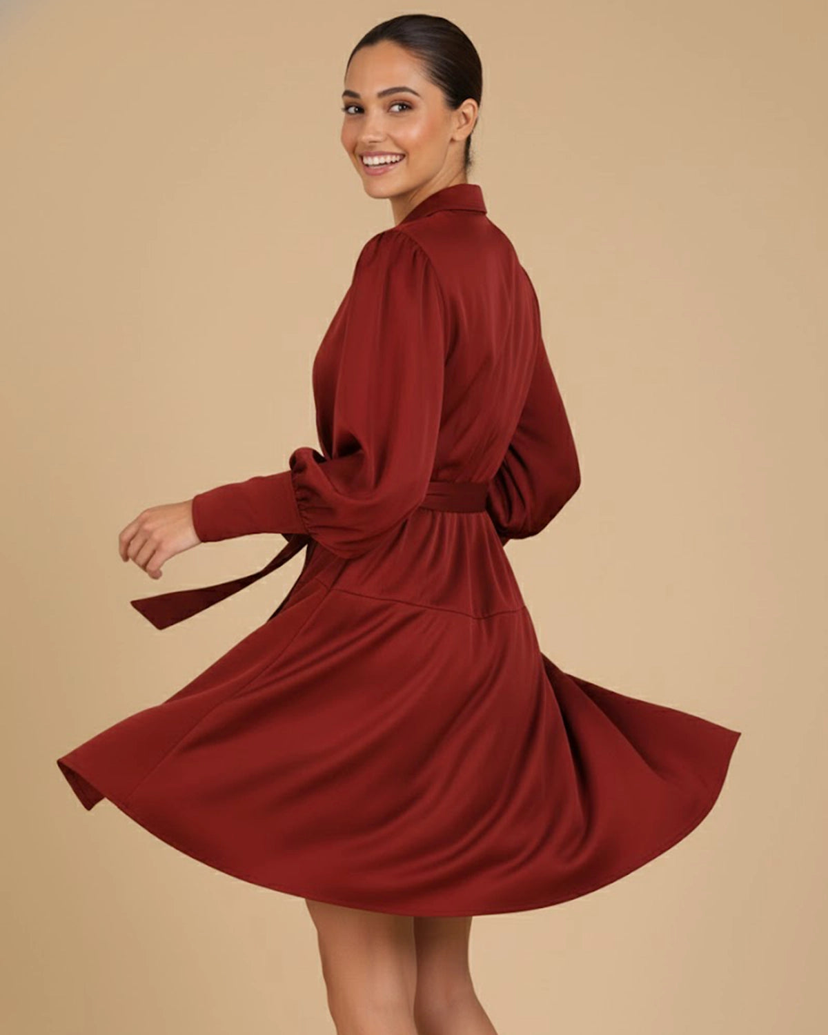 Model happily twirling in the Elye Sustainable Mini Wrap Dress in Deep Burgundy Red, showcasing the flare and movement of the mini skirt.