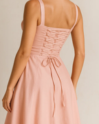 The Heidi corset milkmaid midi dress in pastel pink, made from sustainable recycled polyester. Shown from the back view. Ethically made in London by ADKN