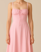 The Heidi corset milkmaid midi dress in pastel pink, made from sustainable recycled polyester. Shown from the front view. Ethically made in London by ADKN