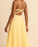 The Soleil pleated midi dress in butter yellow, made from sustainable recycled polyester. Shown from the back view. Ethically made in London by ADKN